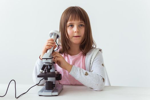 Schoolgirl using microscope in science class. Technologies, lessons and children.