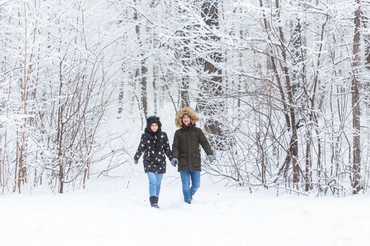 Young couple in love walks in the snowy forest. Active winter holidays