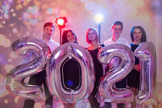 Party and new year holidays concept - women and men celebrating new years eve 2021