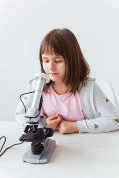 Portrait of cute little child doing homework with a digital microscope Technologies, science and children.