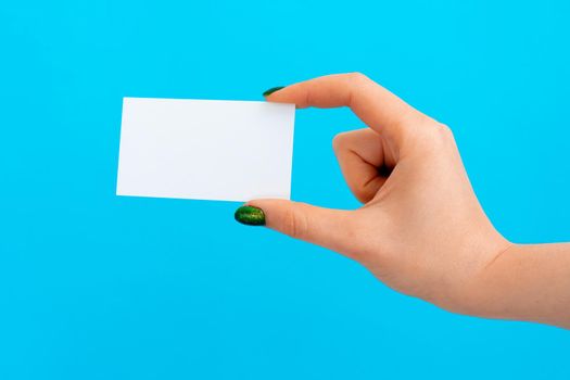 Woman hand holding blank card on blue background, close up.