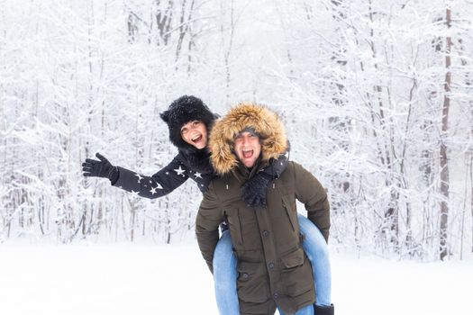 Portrait of happy young couple in winter park with their friend behind.