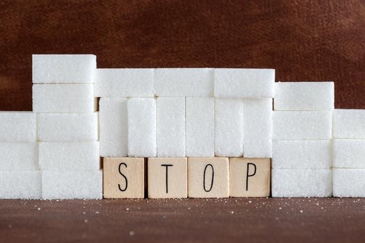 Pile or wall of sugar cubes and stop word in block letters as advise on addiction calories excess and sweet unhealthy food abuse causing health problem and overweight background concept.