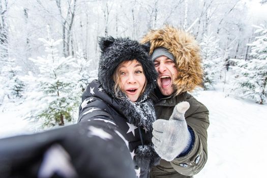 Season and relationship concept - Funny couple taking selfie in the winter time.