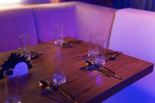 Served table with glasses, plates and cutlery in a restaurant for dinner, closeup view