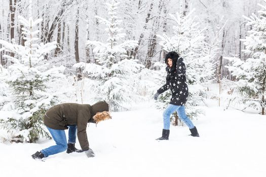 Fun, season and leisure concept - love couple plays winter wood on snow.