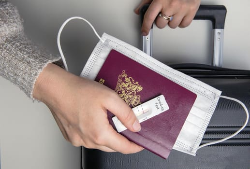 COVID-19, travel and lockdown concept, Young womans hand with passport,medical mask and negative rapid test coronavirus and suitcase, Travel,requirement,health,covid and holiday concept pandemic