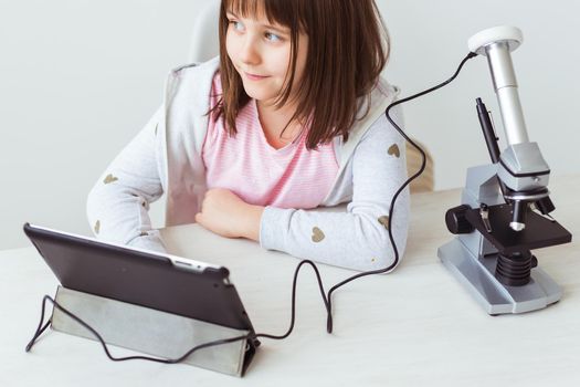 Child girl in science class using digital microscope. Technologies, children and learning.