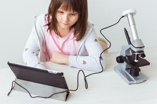 Portrait of cute little child doing homework with a digital microscope Technologies, science and children.