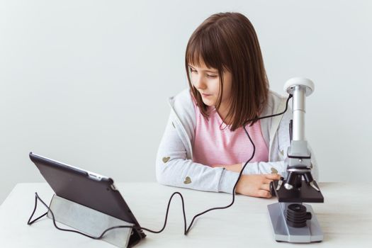 Child girl in science class using digital microscope. Technologies, children and learning.