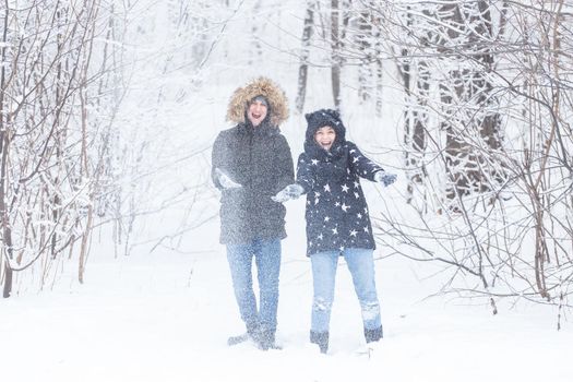 Young couple playing with snow in winter park.