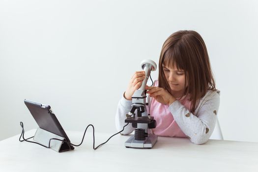 Child girl in science class using digital microscope. Technologies, children and learning.