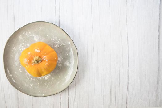 Orange pumpkin on white wooden background with copy space on natural plate top view, autumn harvest, Halloween or Thanksgiving concept space for text