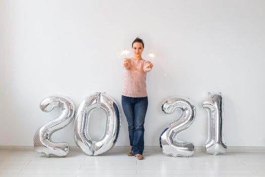 New Year celebration and party concept - Happy young woman with sparklers near silver 2021 balloons on white background