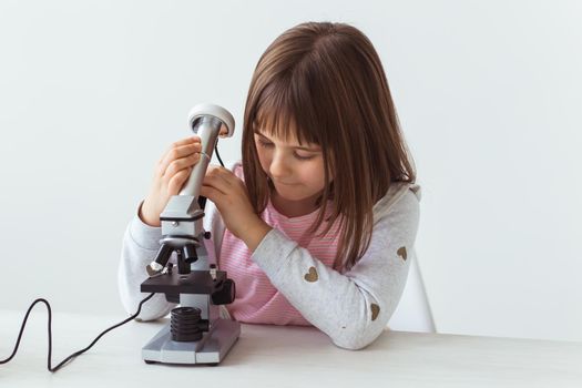 Schoolgirl using microscope in science class. Technologies, lessons and children.