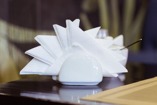 White napkins in holder on wooden table