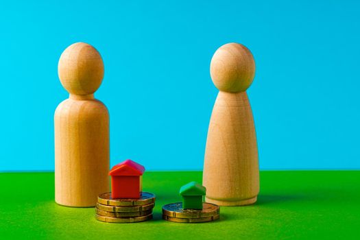 Wooden family with toy house and stack of coins close up. Savings for house purchase concept