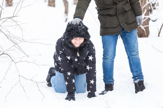 Fun, season and leisure concept - love couple plays winter wood on snow.