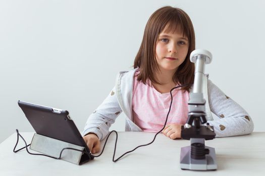 Portrait of cute little child doing homework with a digital microscope Technologies, science and children.