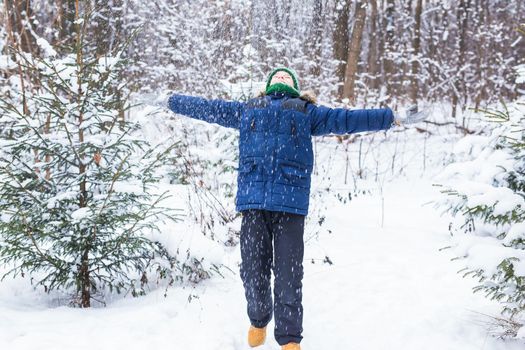 Young boy plays with snow, have fun, smiles. Teenager in winter park. Active lifestyle, winter activity, outdoor winter games, snowballs.