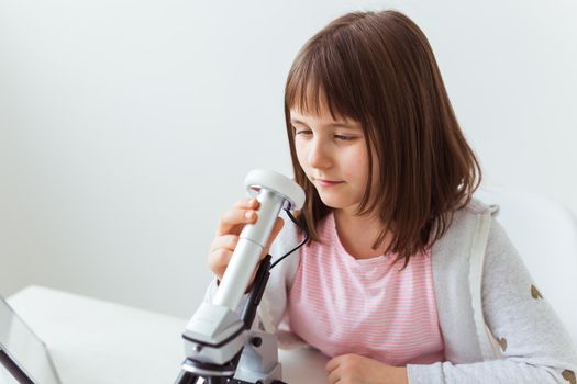 Child girl in science class using digital microscope. Technologies, children and learning.