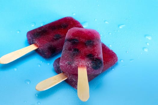 Homemade healthy blueberry ice popsicle on fresh blue background, summer design with copy space colorful bright colors beauty