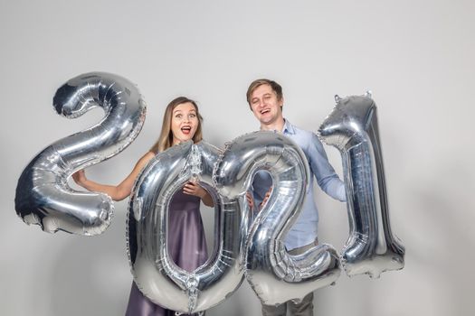 Party, people and new year holidays concept - woman and man celebrating new years eve 2021.