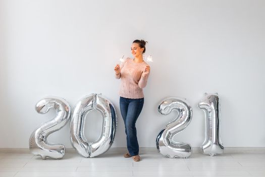 New Year celebration and party concept - Happy young woman with sparklers near silver 2021 balloons on white background