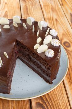 Cut chocolate cake on plate on wooden table close up