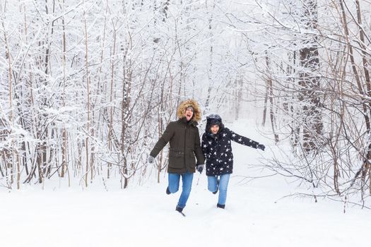 Happy couple walking through a snowy forest in winter.