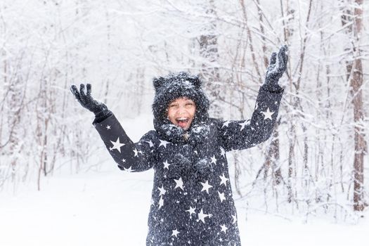 Happy girl throw up a snow in a winter forest