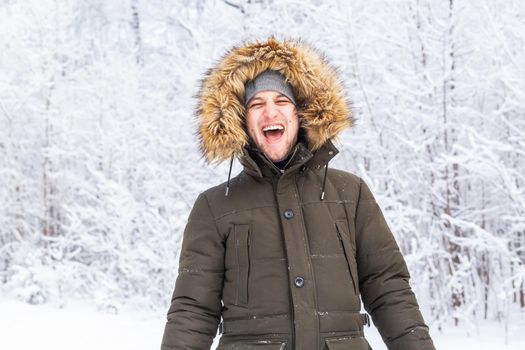 Handsome man in winter hat smiling portrait on snowy nature.