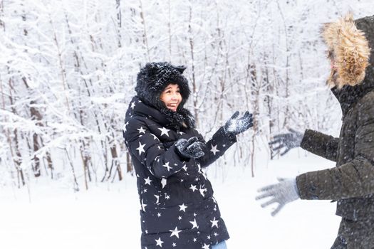 Young couple in a bright clothes throw up a snow in a winter forest