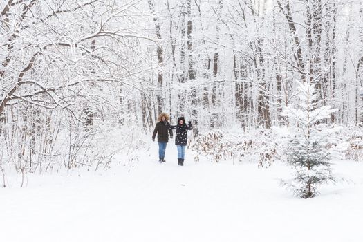 Happy couple walking through a snowy forest in winter.