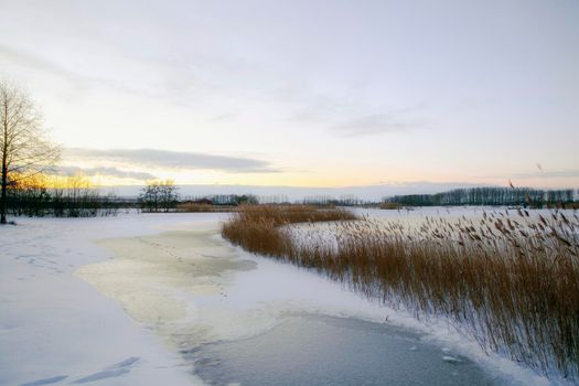 Beautiful winter landscape at sunset with fog and snow covering farmland and river in the Netherlands beautiful colors in nature winter