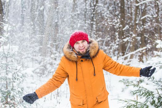 Young man throwing snow in winter forest. Guy having fun outdoors. Winter activities