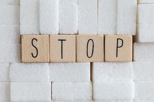 Pile or wall of sugar cubes and stop word in block letters as advise on addiction calories excess and sweet unhealthy food abuse causing health problem and overweight background concept.