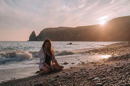 Selective focus. Happy carefree sensual woman with long hair in black swimwear posing at sunset beach. Silhouette of young beautiful playful positive woman outdoor. Summer vacation and trip concept.