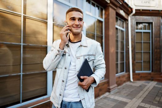 Young casual man walking on the city street and talking on the phone, close up portrait