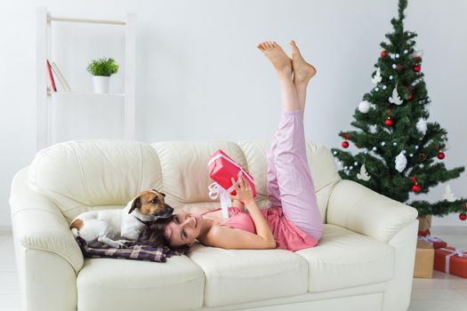 Happy young woman with lovely dog in living room with christmas tree. Holidays.