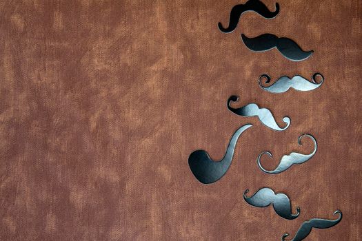 Black mustache and hat on brown leather background texture with copy space, International Men's day and Fathers Day concept space for text