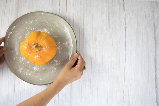 Orange pumpkin on white wooden background with copy space on natural plate top view, autumn harvest, Halloween or Thanksgiving concept space for text