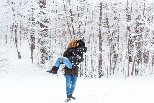 Young couple in love walks in the snowy forest. Active winter holidays