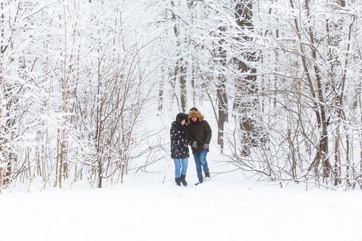 Young couple in love walks in the snowy forest. Active winter holidays