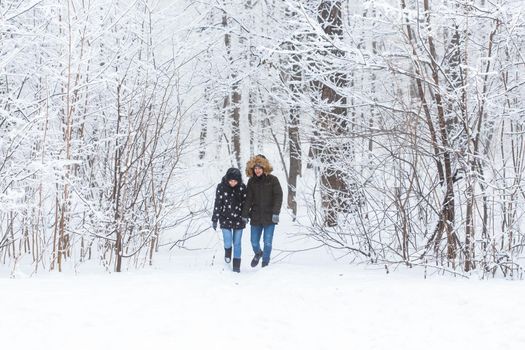 Happy loving couple having fun outdoors in snow park. Winter vacation.