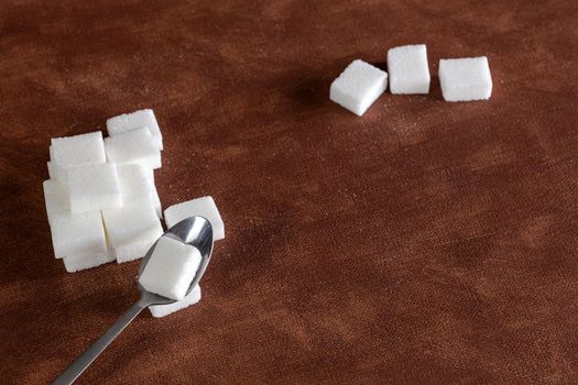 Sugar cubes with spoon top view on brown natural colored background texture with copy space, Sugar,sweet,health,food concept food