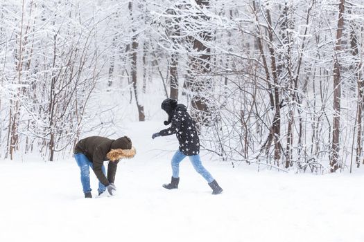 Fun, season and leisure concept - love couple plays winter wood on snow.