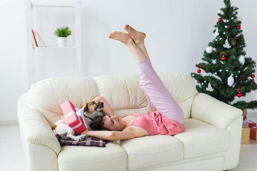 Happy young woman with lovely dog in living room with christmas tree. Holidays.