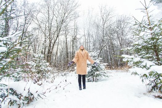 Young woman throwing snow in the air at sunny winter day, she is happy and fun