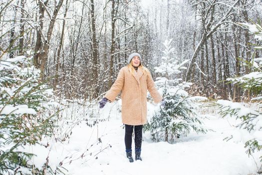 Young woman throwing snow in the air at sunny winter day, she is happy and fun